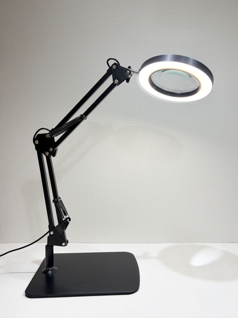 四角い土台に立てたライト付きスタンドルーペ。レンズのまわりのLEDライトが点灯している